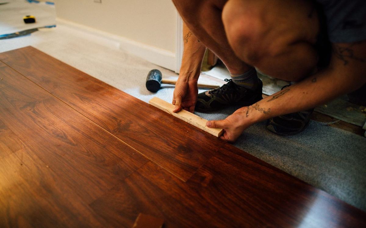 Fitter tapping laminate boards together during installation