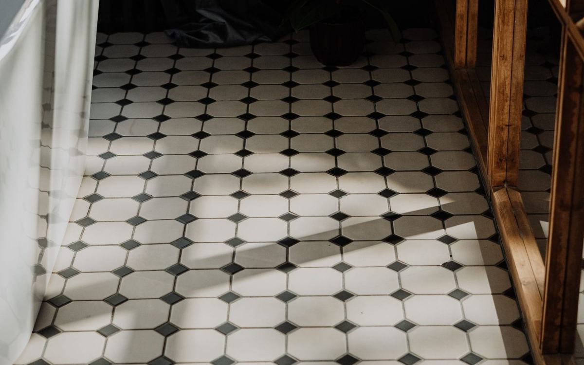 Black and white patterned bathroom floor beside a freestanding bath